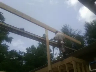Carpenter setting a ridge beam over a new addition frame — Ice Dam Removal by Roofing Brothers in Loraine