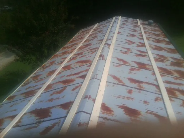 Rusted metal roof panels with new wood purlins before replacement — Storm Damage Roof Repair in Loraine by Roofing Brothers
