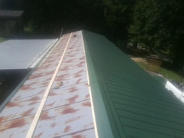 Old rusted panels beside newly installed green metal roofing — Wind Damage Roof Repair by Roofing Brothers in Loraine
