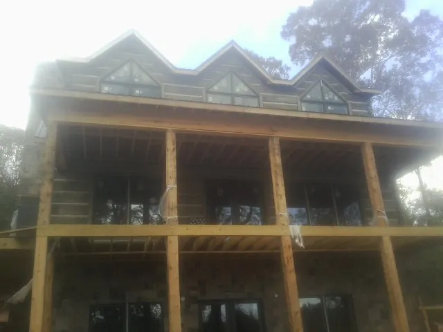 Dormers and porch framing on a large log home under construction — Roof Coating work by our crew in Loraine