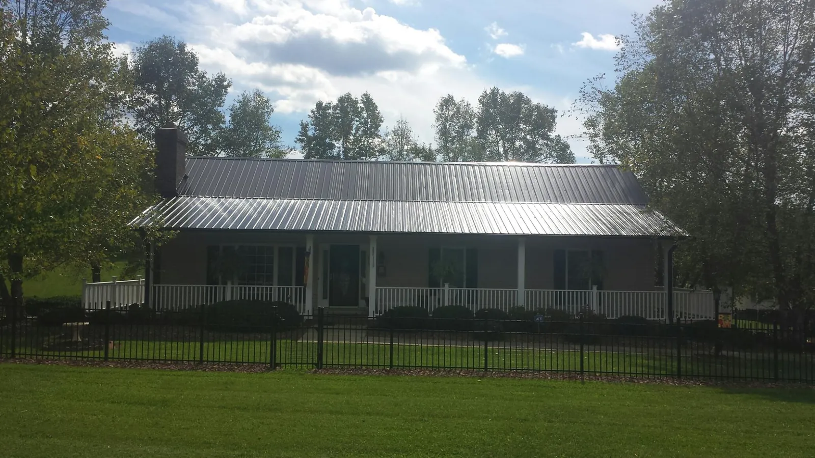 Gray metal roof on a brick ranch with a full width front porch — Gutter Guard Installation work by our crew in Loraine