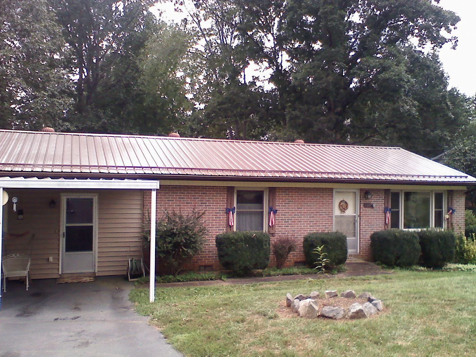 Bronze metal roof and carport on a brick ranch home — Roof Repair work by our crew in Loraine